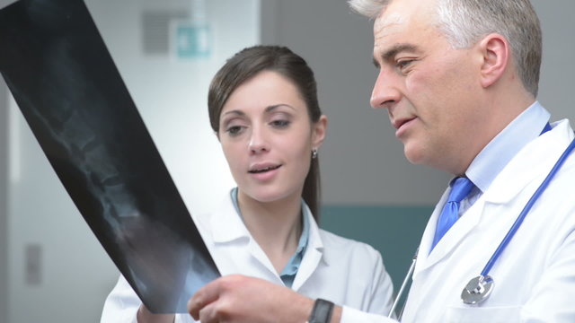 Doctor and assistant looking at patient's x-ray and pointing.