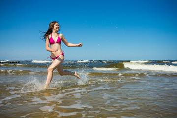 Teenage girl running, jumping on beach