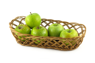 Ripe gren apples in long brown wicker basket isolated closeup
