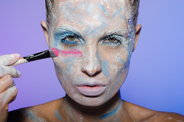 Woman paints her face with colors