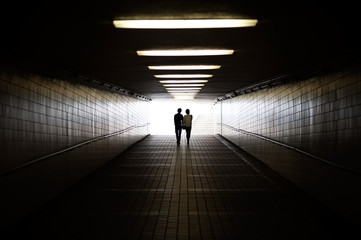 Couple in silhouette walking towards pedestrian underpass exit