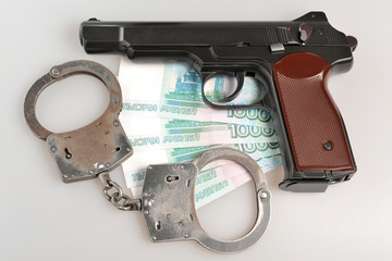 Pistol with handcuffs and money isolated on gray