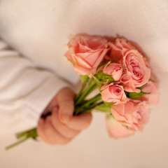 Newborn baby hand holding pink roses.