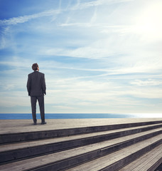 business man standing on a pier looks the sea