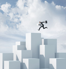 Businessman jumping on a highest cube