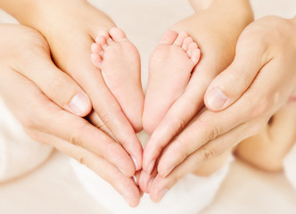 Newborn baby feet in parents hands. Love simbol as heart sign - obrazy, fototapety, plakaty