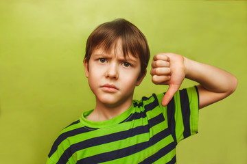 baby boy showing teenager thumbs down on the big green backgroun