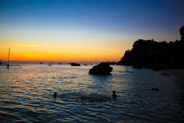 Fototapeta na wymiar Colorful beautiful sunset with sailboat on the horizon in