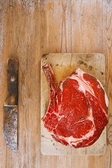 Bone-in Rib eye Steak steak on paper and wooden table