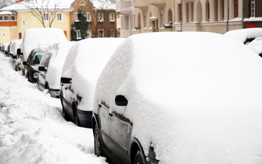 Snow covered cars on a street in a european City