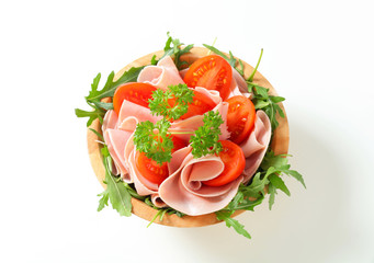 Sliced ham with arugula and tomatoes