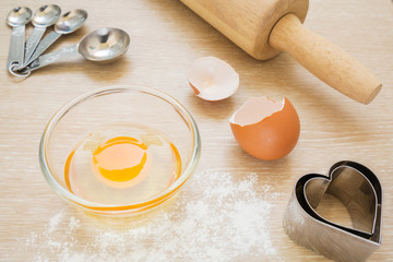 Baking utensils, egg in bowl and flour.