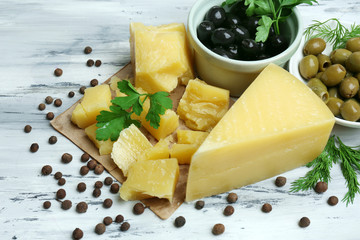 Parmesan cheese, fresh herbs and olives on wooden background