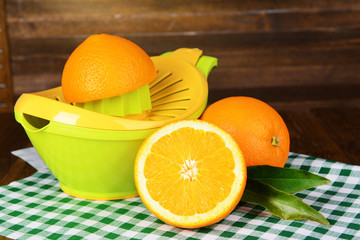Citrus press and oranges on table on wooden background