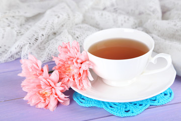 Pink chrysanthemums and cup of tea on wooden table