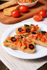 Delicious bruschetta with tomatoes on plate on table close-up