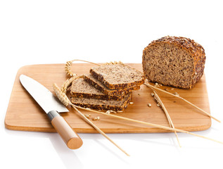 Fresh bread being sliced on a wooden cutting board with a bread