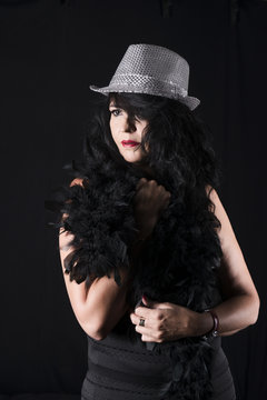 Sensual burlesque woman in black with feathers and silver hat