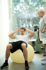 Obraz premium Personal trainer shows to a senior man how to do exercise 