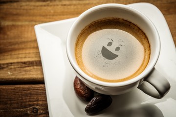 Coffee cup on a wooden table with smiley in it