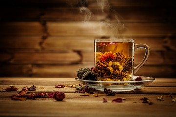 Tasse en verre avec fleur de thé sur fond de bois