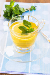 Cup of tea with mint and lemon on a wooden surface