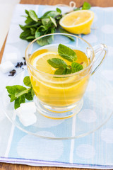 Cup of tea with mint and lemon on a wooden surface