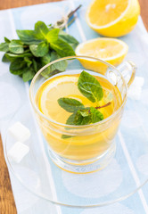 Cup of tea with mint and lemon on a wooden surface