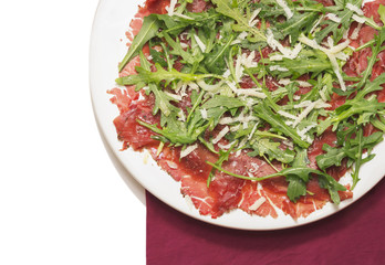 Carpaccio of beef with rucola and Parmesan on red napkin