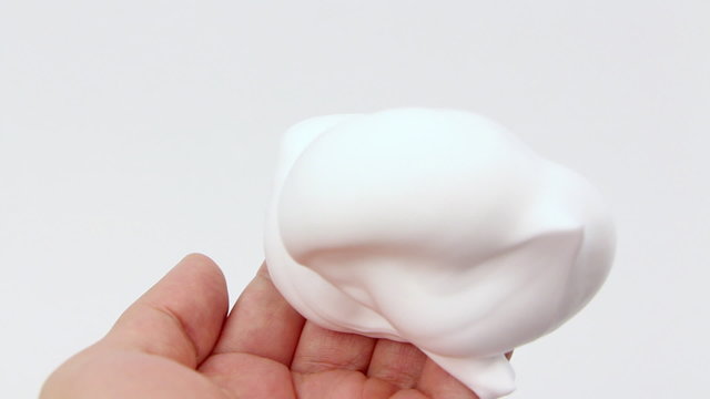 White shaving foam is squeezed in the palm of a hand