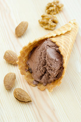Soft chocolate ice cream in waffle cone on a wooden surfase