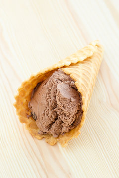 Soft chocolate ice cream in waffle cone on a wooden surfase