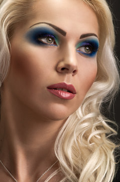 face of young woman with makeup on dark  background