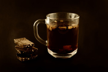 Cup of tea with herbs and pieces of chocolate with crushed nuts