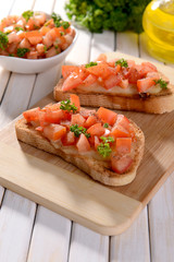 Delicious bruschetta with tomatoes on cutting board close-up