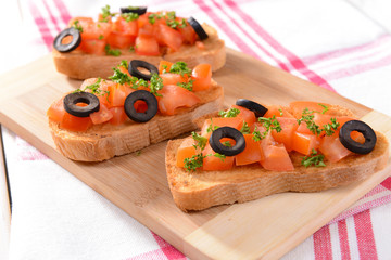 Delicious bruschetta with tomatoes on cutting board close-up