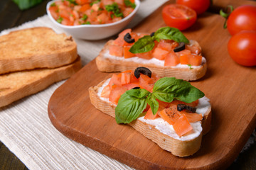Delicious bruschetta with tomatoes on cutting board close-up