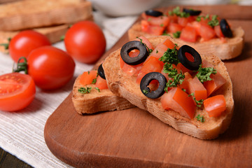 Delicious bruschetta with tomatoes on cutting board close-up