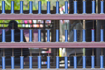 Blue reels of textile yarn thread at manufacturing machine.