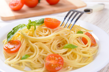 Delicious spaghetti with tomatoes on plate on table close-up