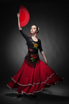 young woman dancing flamenco with fan on black