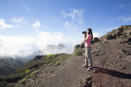woman nature photographer taking pictures outdoors during hiking