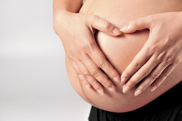 Pregnant Woman holding her hands in a heart shape on her baby
