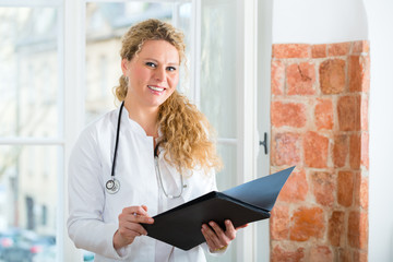 Ärztin in Praxis liest Krankenakte