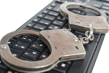 Handcuffs on the keyboard on white background