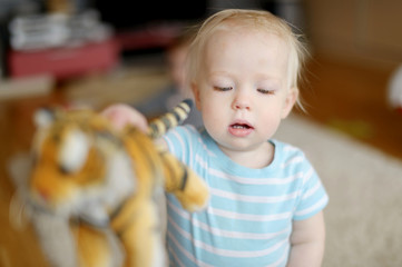 Fototapeta premium Adorable little girl playing with a toy tiger
