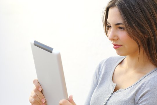 Close up of a young woman reading a tablet reader outdoors
