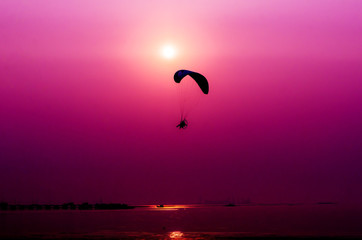 Paramotor flying on sunset background