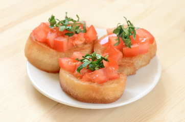 Toasted bread with tomatoes on white plate