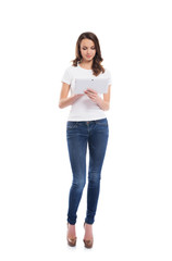 A young girl in stylish jeans holding a tablet computer